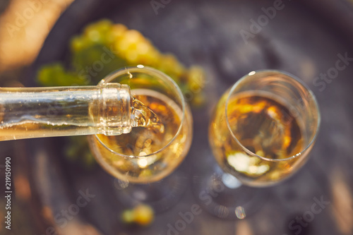 Pouring white wine into glasses, top view.