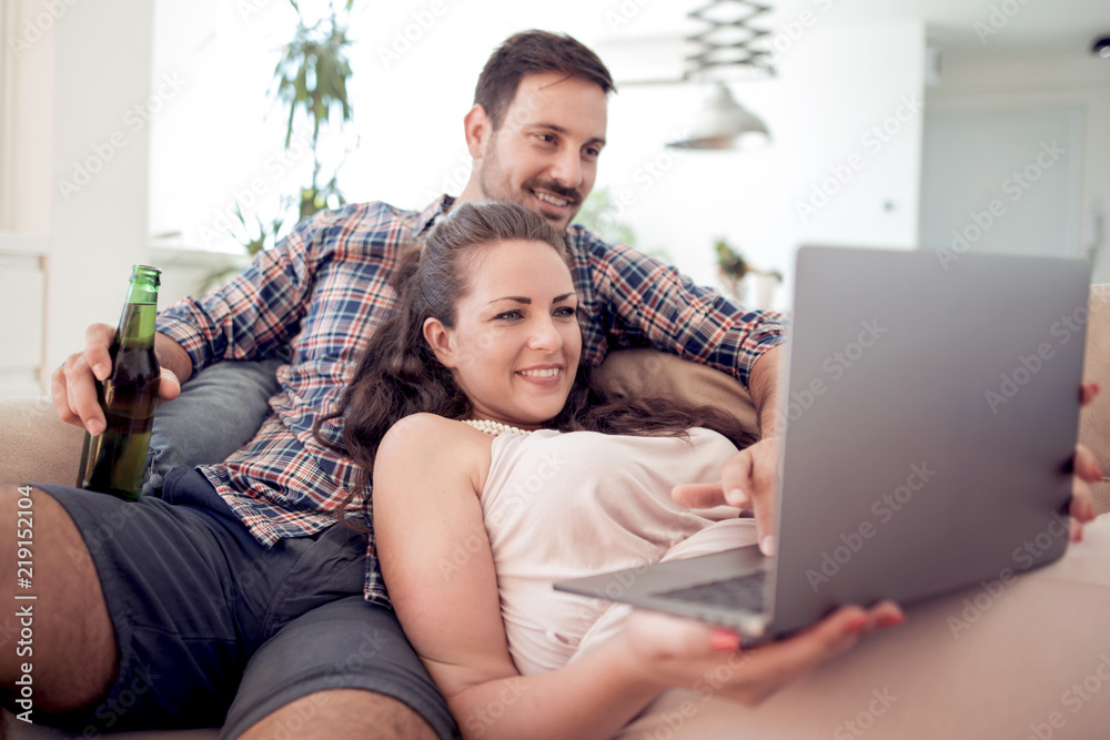 Couple sitting on sofa and using laptop in living room
