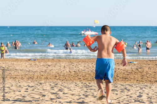 beautiful, sandy beach in a tiny resort near Side full of unidentified tourists. A boy going to the water