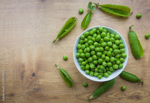 A bowlful of freshly picked and podded homegrown garden peas on a wooden table top photo