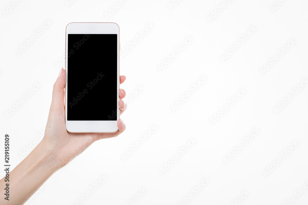 Female left hand holding smartphone with blank screen on white background Female left hand holding smartphone with blank screen on white background
