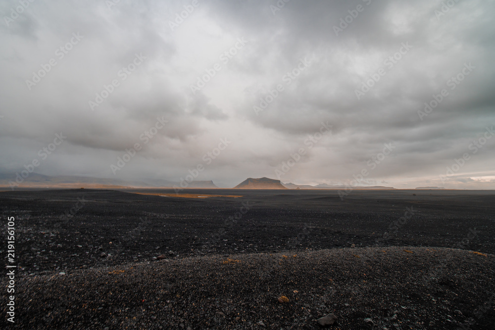 Black landscape of Iceland against the background of mountains in gray clouds