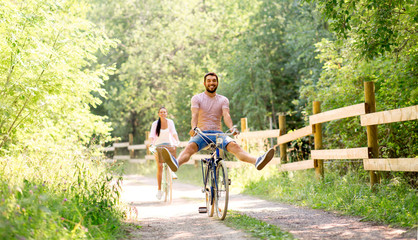 cycling, leisure and lifestyle concept - happy young couple with bicycles at summer park