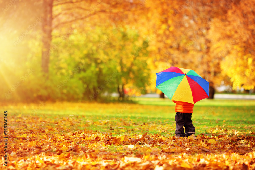 Child standing with umbrella in beautiful autumnal day