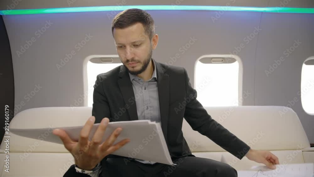 Portrait of male investor analyzing market situation on paper report during the flight on his private entrepreneur plane. Concept of: lawyer, business people, plane flying, paper work, graphs and Portrait of male investor analyzing market situation on paper report during the flight on his private entrepreneur plane. Concept of: lawyer, business people, plane flying, paper work, graphs and