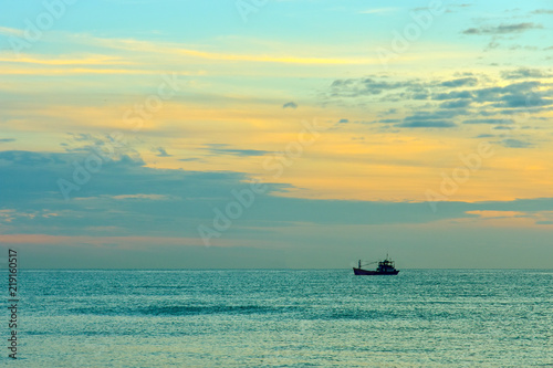 Small silhouette of a fishing boat against a sunset background