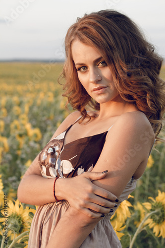 Young beautiful woman wearing a hat in a field of sunflowers