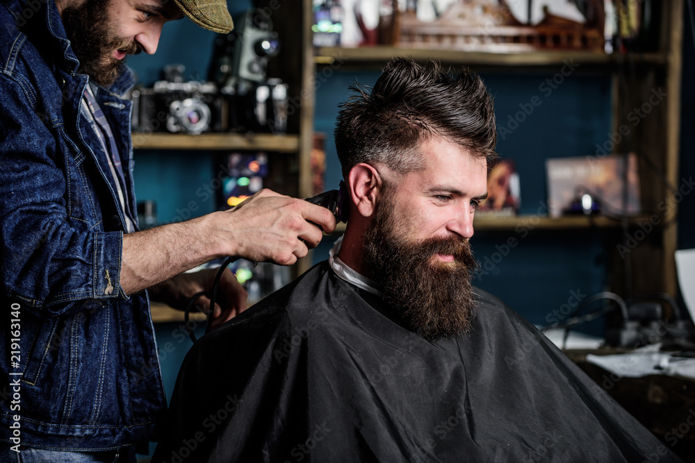 Barber with hair clipper works on haircut of bearded guy barbershop background. Hipster client getting haircut. Hipster hairstyle concept. Barber with clipper trimming hair on nape of client Barber with hair clipper works on haircut of bearded guy barbershop background. Hipster client getting haircut. Hipster hairstyle concept. Barber with clipper trimming hair on nape of client