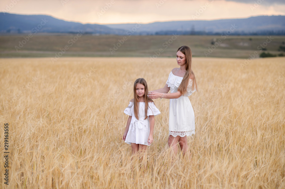 Beautiful family in a field of rye at sunset. A woman and child in amazing clothes walking through the field of rye. Beautiful family in a field of rye at sunset. A woman and child in amazing clothes walking through the field of rye.