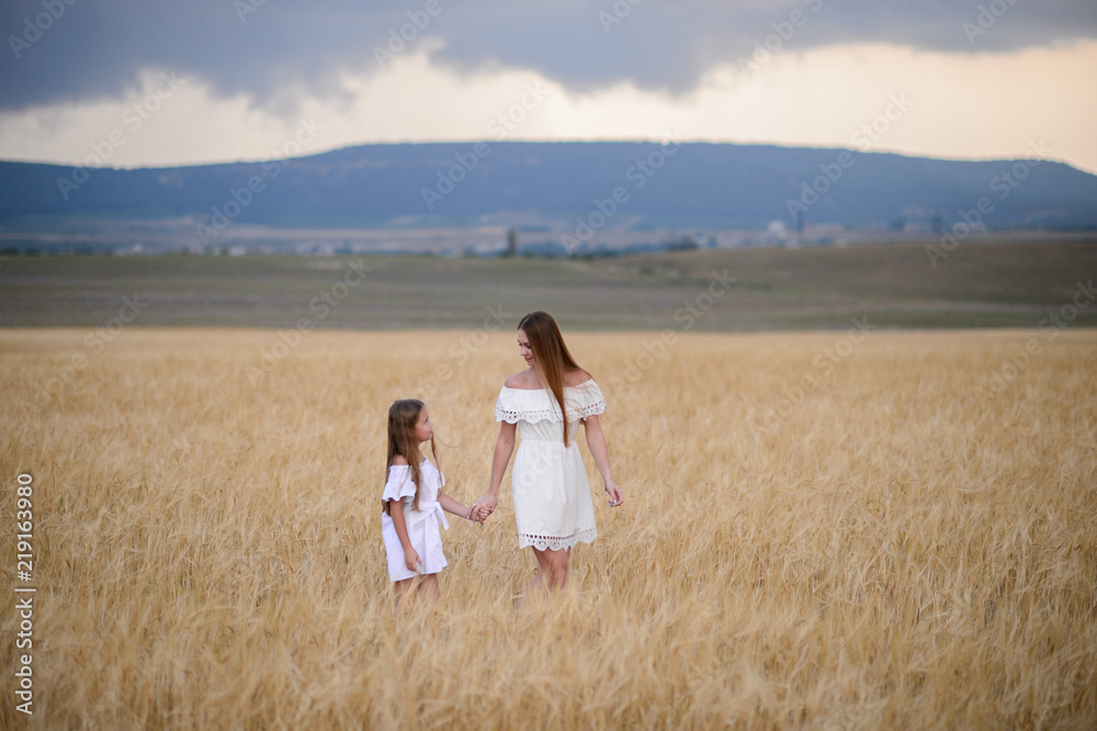Beautiful family in a field of rye at sunset. A woman and child in amazing clothes walking through the field of rye. Beautiful family in a field of rye at sunset. A woman and child in amazing clothes walking through the field of rye.