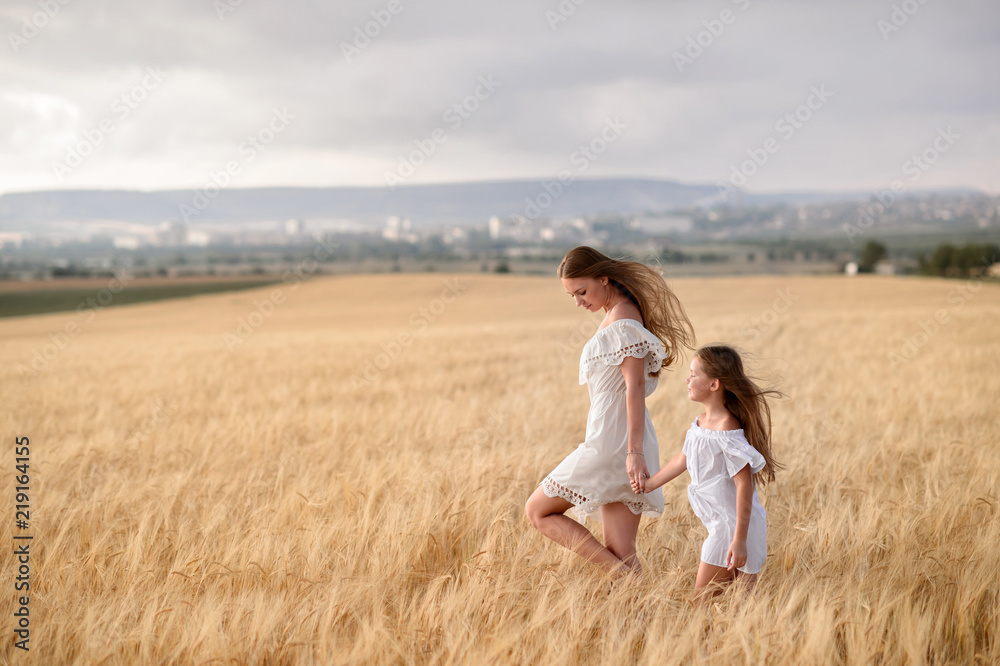 Beautiful family in a field of rye at sunset. A woman and child in amazing clothes walking through the field of rye. Beautiful family in a field of rye at sunset. A woman and child in amazing clothes walking through the field of rye.