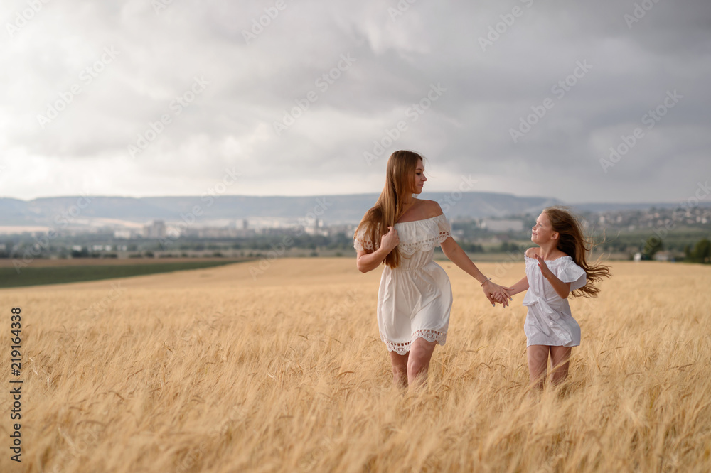 Beautiful family in a field of rye at sunset. A woman and child in amazing clothes walking through the field of rye. Beautiful family in a field of rye at sunset. A woman and child in amazing clothes walking through the field of rye.