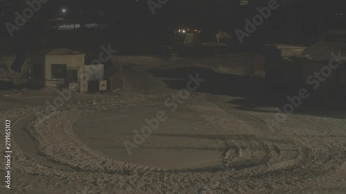 BELOKURIKHA, RUSSIA - MARCH 8, 2018: Red ratrak clears snow in the ski resort at night. A strong snowstorm on the mountainside. S-log, ungraded, no color.