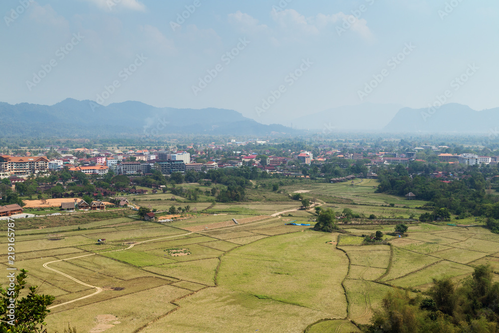 Beautiful view of town and fields from above in Vang Vieng, Vientiane Province, Laos, on a sunny day.