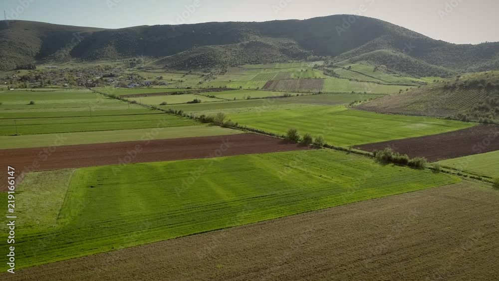 Aerial view of grass fields surrounded by vegetation and hills. Aerial view of grass fields surrounded by vegetation and hills.