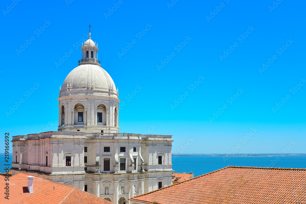 View of The National Pantheon,Panteão Nacional (Church of Santa Engracia) between clay roof from the rooftop on the hill at Alfama district in Lisbon, Portugal. View of The National Pantheon,Panteão Nacional (Church of Santa Engracia) between clay roof from the rooftop on the hill at Alfama district in Lisbon, Portugal.