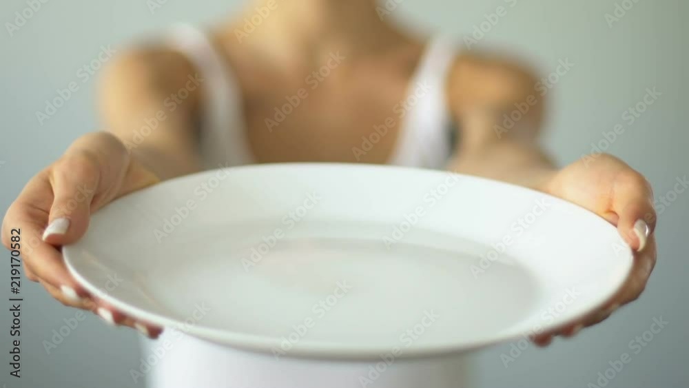 Diet concept, girl with taped mouth holding empty plate, malnutrition, anorexia Diet concept, girl with taped mouth holding empty plate, malnutrition, anorexia