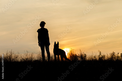 Girl and dog at sunset .