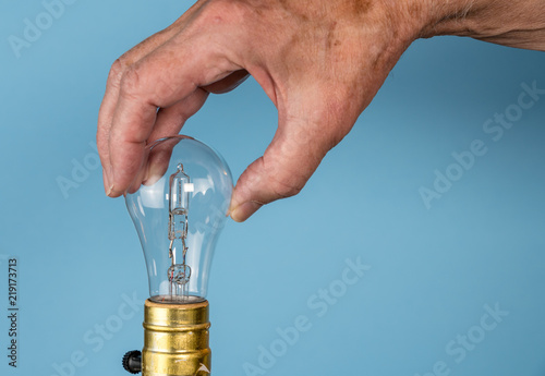 Senior man hand unscrewing the halogen bulb