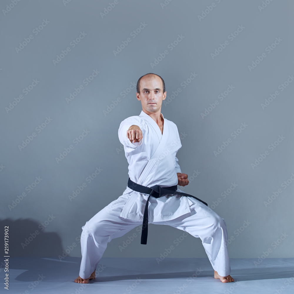 The athlete strikes with a hand in the karate rack against a dark background The athlete strikes with a hand in the karate rack against a dark background