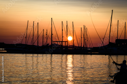 Sunset over marina in Croatia with fisherman