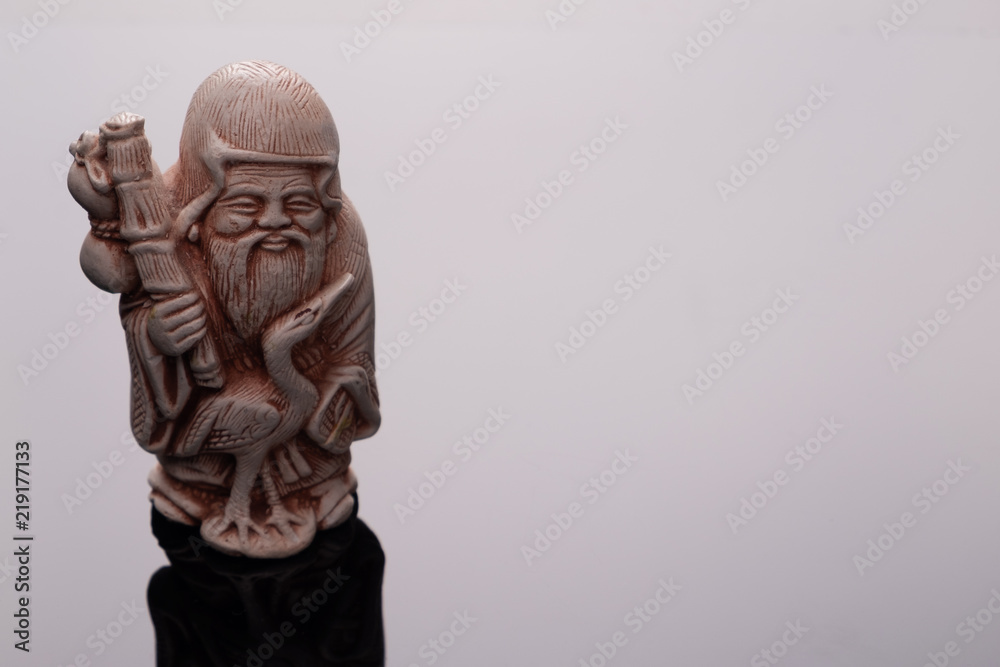 statue of an old man, symbol of health in Buddhism, black background