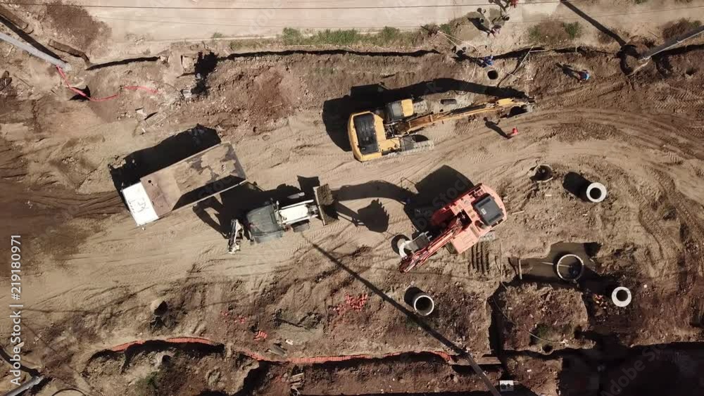 Aerial construction site with machinery, bulldozer, excavation. Top down view of city building site.