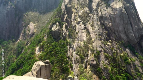 Panning up massive stairs up the side of Chinese Huangshan mountain. Very long staircase up Yellow Mountain in China. Walking up thousands of steps to the top peak for tourists. photo