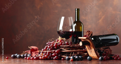 Red wine and fresh grapes with dried up vine leaves.