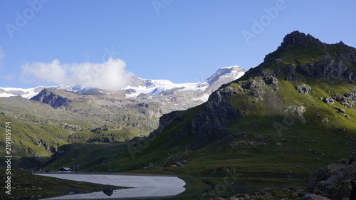 Alpejski wysokogórski lodowcowy krajobraz z skalista górą na pierwszym planie.