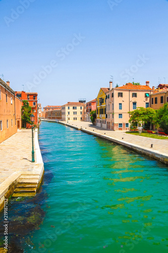 View on the historic architecture and the canal between the ancient buildings in Venice, Italy on a sunny day.