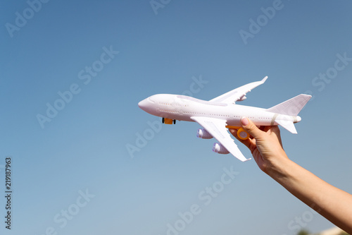 Plane in female hand clear blue sky background copy space. Travel and vacation. Book tickets now. Toy white plane fly vacation destinations. Travel comfortable premium class airlines. Discover world