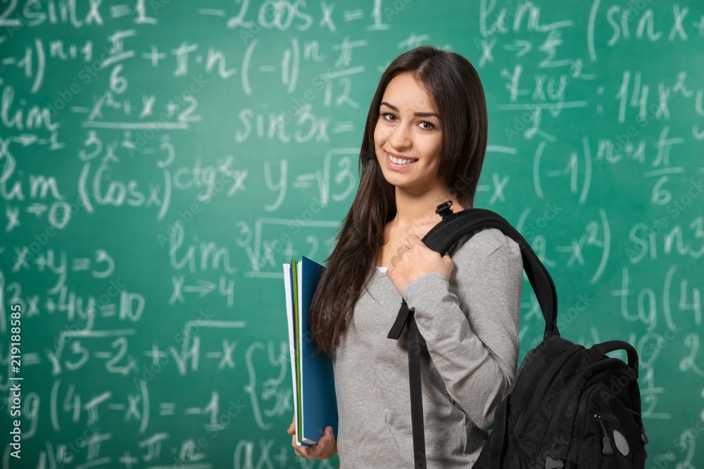 Young female student on blurred chalkboard background