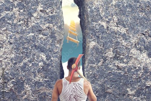 Fotografija A man with a pick on his shoulder near a broken granite wall