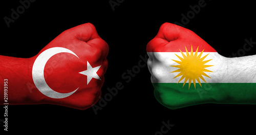 Flags of Turkey and Kurdistan painted on two clenched fists facing each other on black background/Turkish- Kurdish conflict concept photo