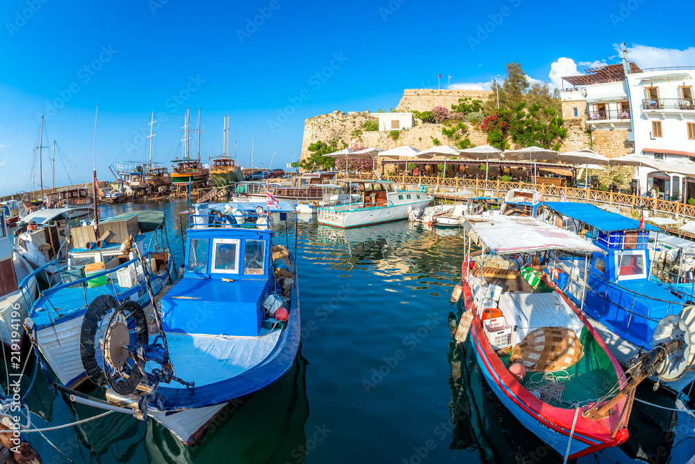 Obraz premium Fishing Boats moored in Kyrenia (Girne) harbour with restaurants and fortress on background