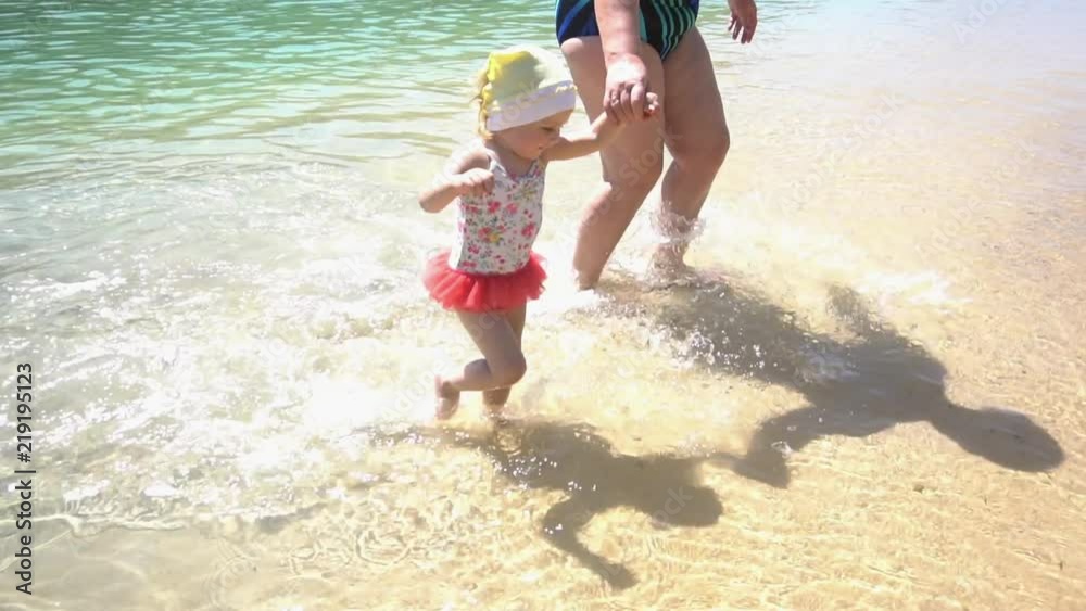 Grandmother and granddaughter are running along the shore of the sea bay Grandmother and granddaughter are running along the shore of the sea bay
