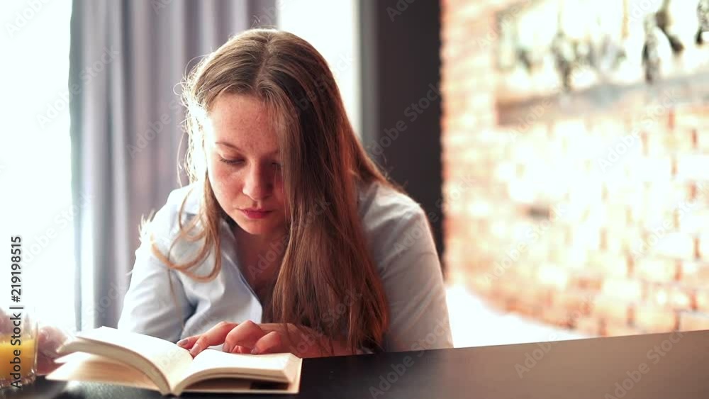 Young, cute woman reading book by table at home
Young, cute woman reading book by table at home