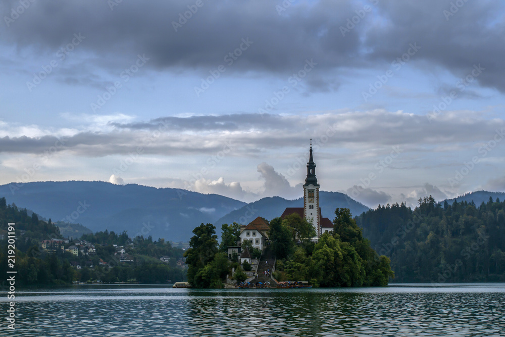 Church situated on an island on Bled lake and mountains in background.  Slovenia, Europe. European travel.
