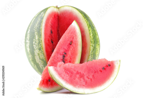 A large ripe watermelon next to watermelon slices on a white isolated background