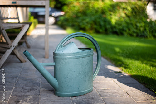 Watering can on a path near lawn