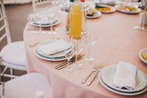 stylish pink table with wine glasses, cutlery, napkin and delicious food and drinks. luxury catering in restaurant. modern wedding reception. pink and white wedding settings © sonyachny