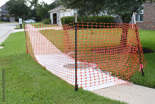 Fresh wet concrete just poured onto sidewalk with red construction fence surrounding site © Bill Doss