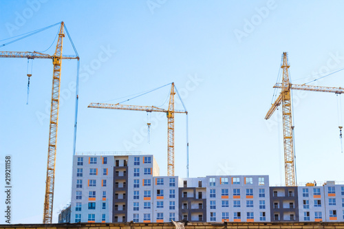 Building cranes and building under construction on blue sky