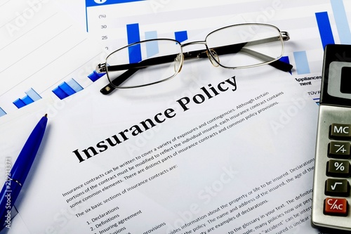 Pen, Calculator and Business Graphs on Insurance Policy Document