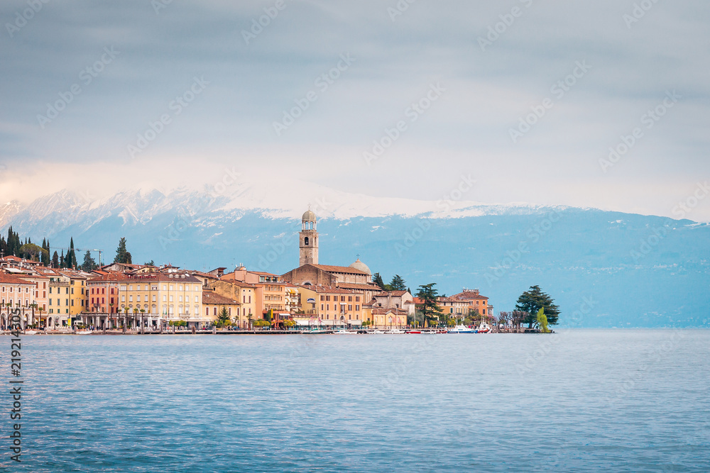 Coastal town Gargnano on Lake Garda, historic pastel-colored buildings and church tower next to the waterfront, Italy