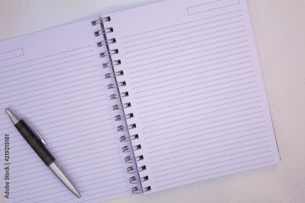 NOTEBOOK WITH BLANK PAGE AND BLACK PEN ON WHITE TABLE NOTEBOOK WITH BLANK PAGE AND BLACK PEN ON WHITE TABLE