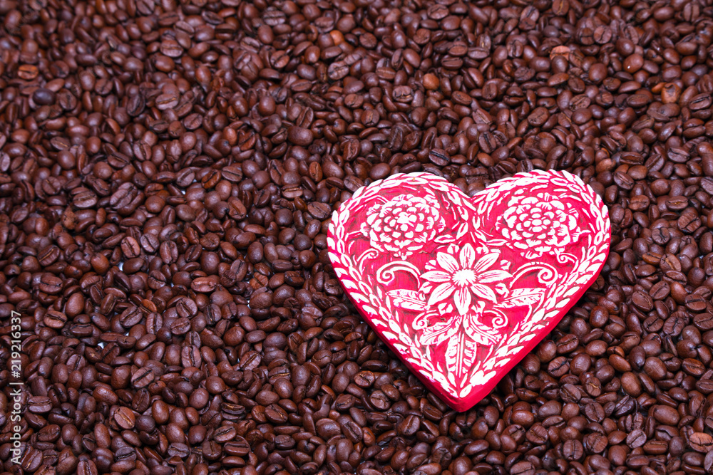 Large red heart with white flowers sitting on top of roasted coffee beans Large red heart with white flowers sitting on top of roasted coffee beans