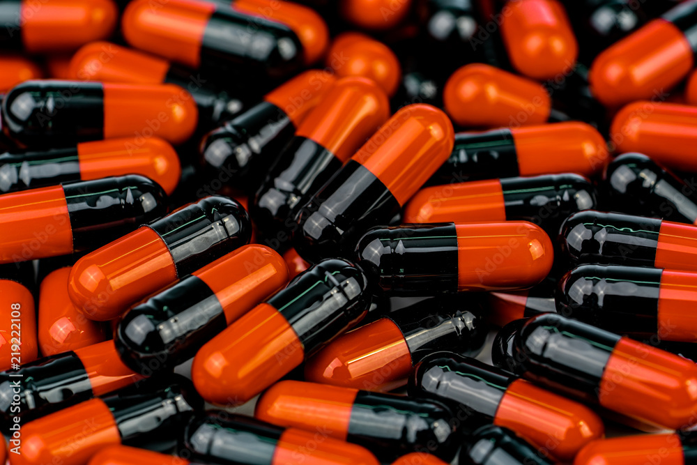 Pile of orange-black capsule pills. Antibiotics resistance. Drug use with reasonable. Global healthcare concept. Antibiotics drug resistance. Antimicrobial capsule pills. Pharmaceutical industry. Pile of orange-black capsule pills. Antibiotics resistance. Drug use with reasonable. Global healthcare concept. Antibiotics drug resistance. Antimicrobial capsule pills. Pharmaceutical industry.