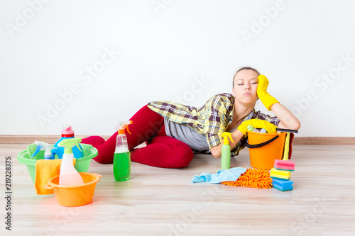 Woman in protective gloves is smiling and wiping dust using a spray and a duster